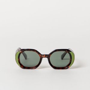 Une paire de lunettes de soleil rondes et surdimensionnées en écaille avec des verres teintés en vert, présentées sur un fond blanc uni.